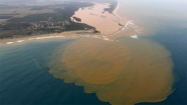 Picture shows the polluted river flowing into the sea, dirty brown water mixing wth blue ocean wtaer